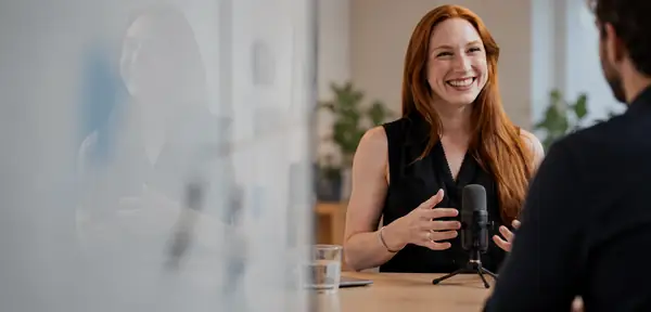 A professional recording a conversation at a desk in a bright office.